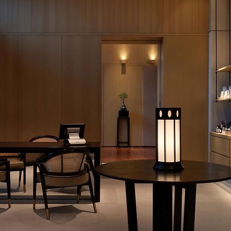 ザ ルーマ ホテル アンド レジデンシーズ クアラルンプール エクステリア 写真 The photo shows a modern, minimalist interior space. It features a wooden wall with soft lighting, enhancing a calm atmosphere. In the foreground, there is a round table with a uniquely designed lamp on it. Surrounding the table, there are stylish wo